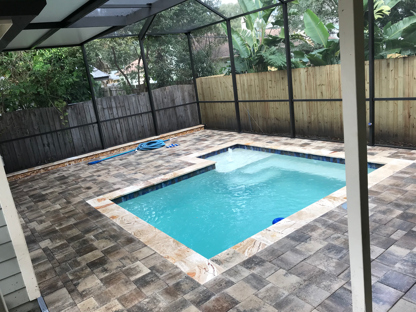 Paver and travertine pool deck and coping plus retaining wall with stone tile